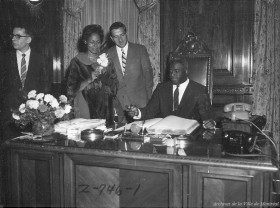 Jackie Robinson signant le livre d’or de la Ville de Montréal en compagnie de son épouse Rachel, 11 septembre 1958. VM94,Z746-1