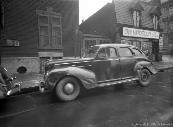 Vol à main armée : voiture accidentée dans le cadre d’un vol, stationnée devant le restaurant Chez Madelon, à côté de la Cour municipale, au coin Gosford et Saint-Louis. - 10 avril 1946. VM095-Y-1-2-1-D05. Archives de la Ville de Montréal.