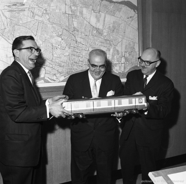 Présentation d’une maquette d’une voiture de métro, en présence du maire Drapeau, de Lucien L'Allier et de Lucien Saulnier. 16 mars 1963. VM94-M015-001. Archives de la Ville de Montréal.
