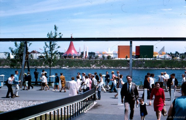 Foule déambulant sur le site d’Expo 67. En arrière-plan, on aperçoit entre autres les pavillons de l’Éthiopie et du Vénézuela, sur l’île Notre-Dame / Gilbert Ouellet. – 1967. - Archives de la Ville de Montréal. P123_1P041