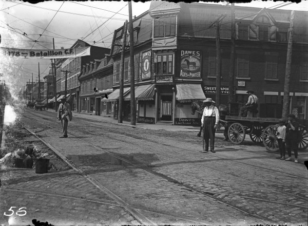 La rue Notre-Dame ouest, à l'intersection de l'avenue Atwater. – Vers 1916. On aperçoit notamment le Social café (476 ave Atwater) et une bannière de recrutement pour le 178e bataillon canadien-français (Première Guerre mondiale). VM117-Y-1P0056. Archives de la Ville de Montréal.