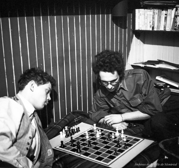 Robert Millet jouant aux échecs avec le chanteur Noël Guyves, à l’atelier de Robert Millet sur la rue Saint-Denis. – 1954. P179-Y-01-02-D001-P048. Archives de la Ville de Montréal.