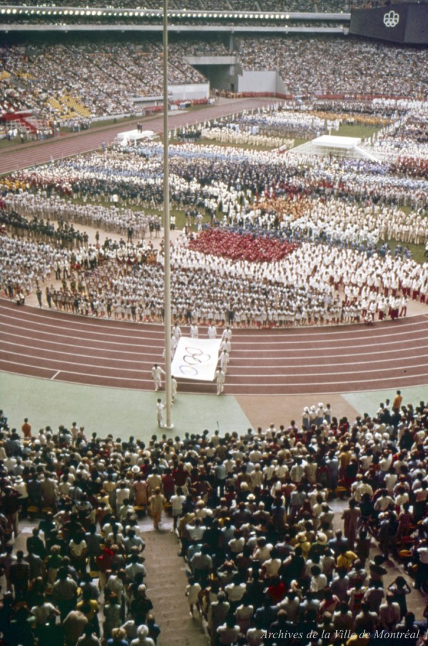 Athlètes qui portent le drapeau olympique au pied du mât. – 17 juillet 1976. VM094-42-08-D8I2 -P029. Archives de la Ville de Montréal.